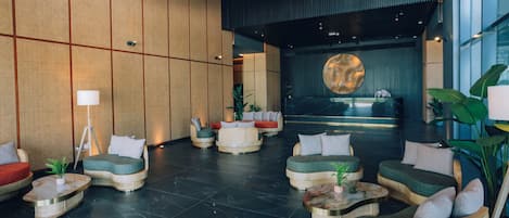A modern lobby with a reception desk, seating areas, and a large decorative wall piece.