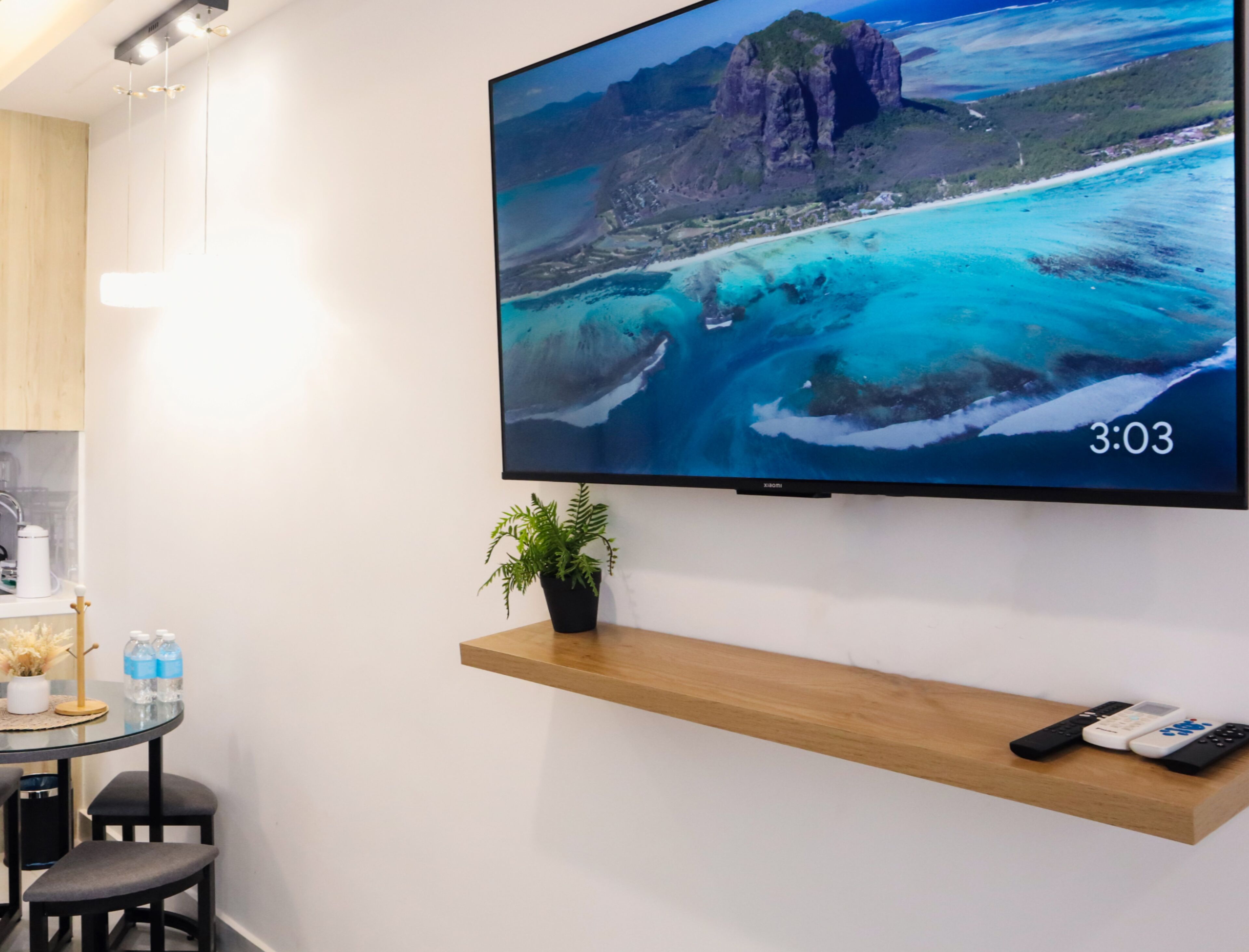 A flat-screen TV mounted on a wall displaying a scenic coastal landscape.