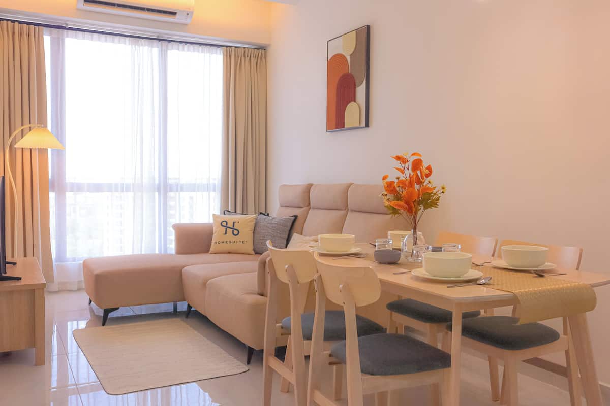 Uma sala de estar moderna com um sofá, mesa de jantar, cadeiras e um vaso com flores.