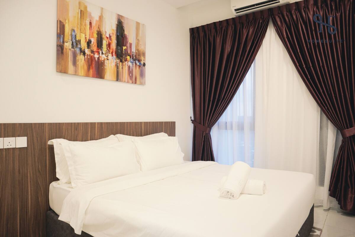 Quarto de hotel com uma cama grande, uma pintura de paisagem urbana e cortinas escuras.