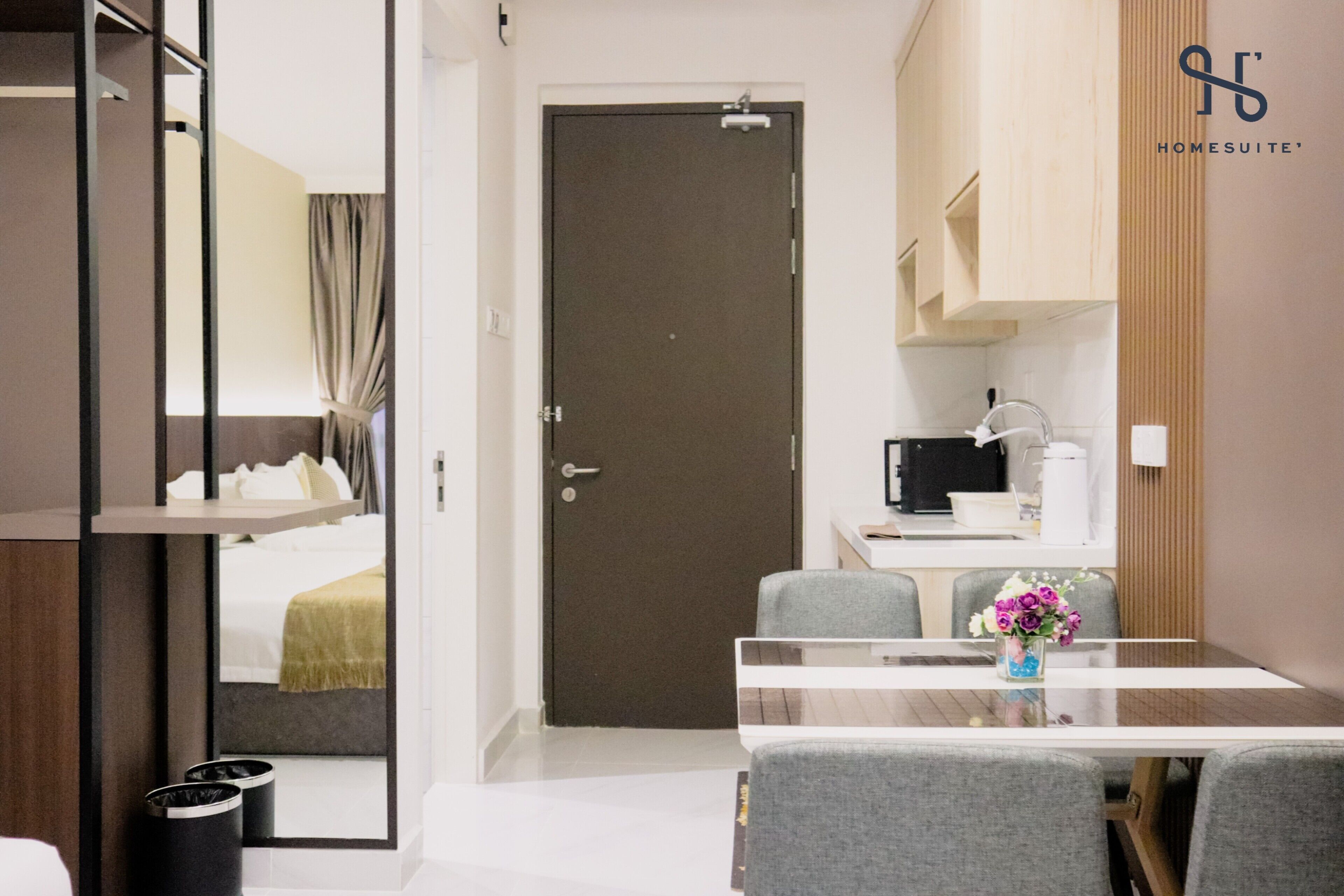 A hotel room with a bed, a bathroom, a kitchenette, and a dining area with a table and chairs.