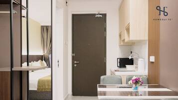 A hotel room with a bed, a bathroom, a kitchenette, and a dining area with a table and chairs.
