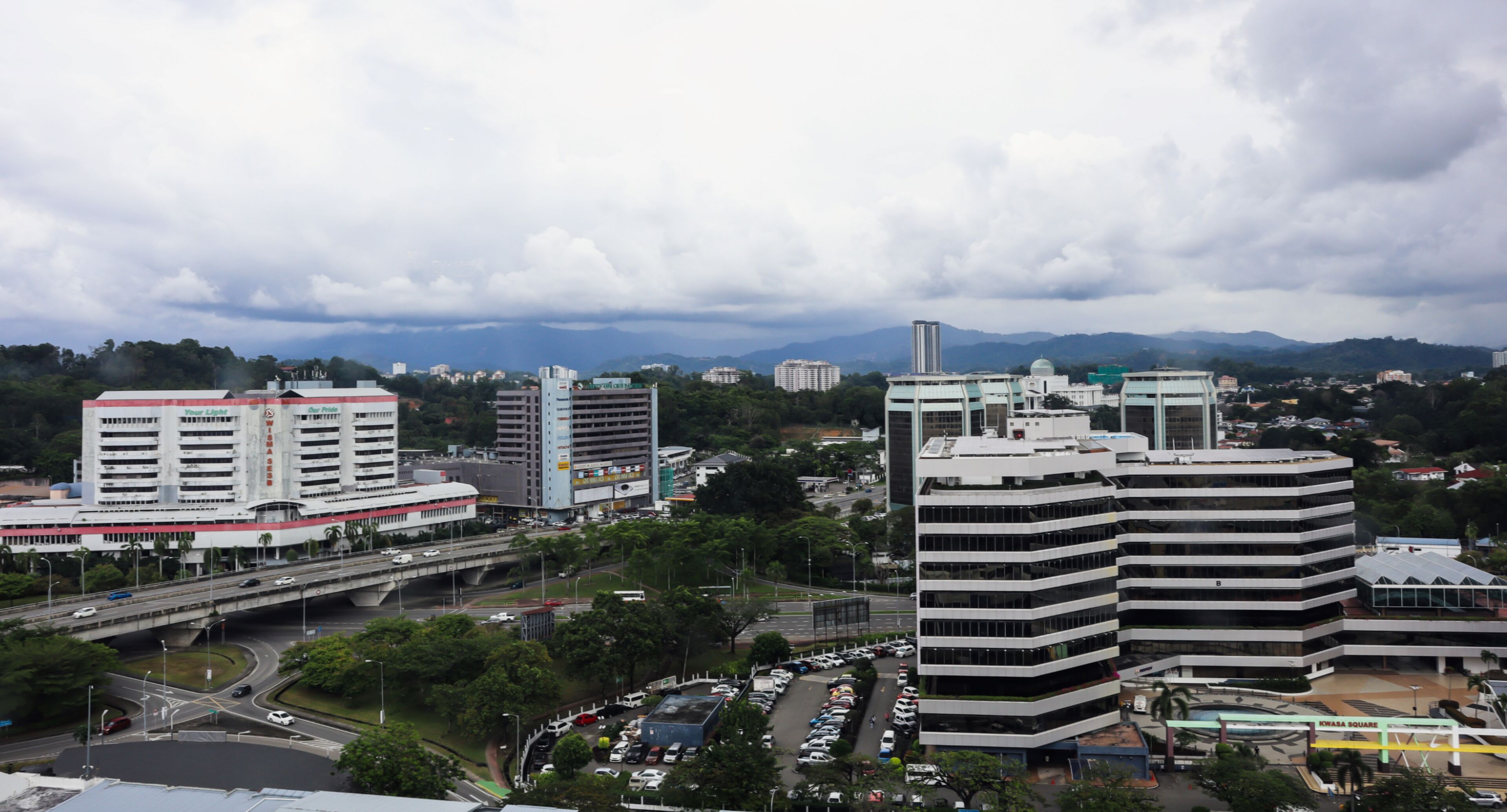 A cityscape with modern buildings, a highway, and a parking lot.