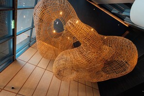 A modern interior with a large, abstract, woven sculpture and a visible elevator. - Homesuite' Home at Sutera Bay (Kota Kinabalu)