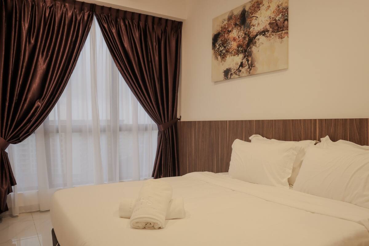 Quarto de hotel com uma cama grande, cabeceira de madeira e um quadro na parede.