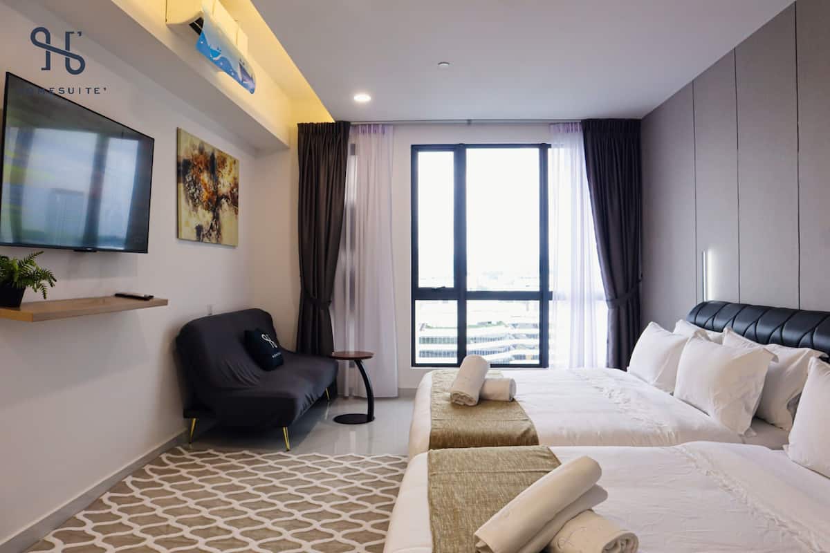 Quarto de hotel moderno com uma cama grande, um sofá, uma televisão e uma janela com cortinas.