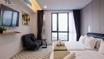 A modern hotel room with a large bed, a sofa, a TV, and a window with curtains.