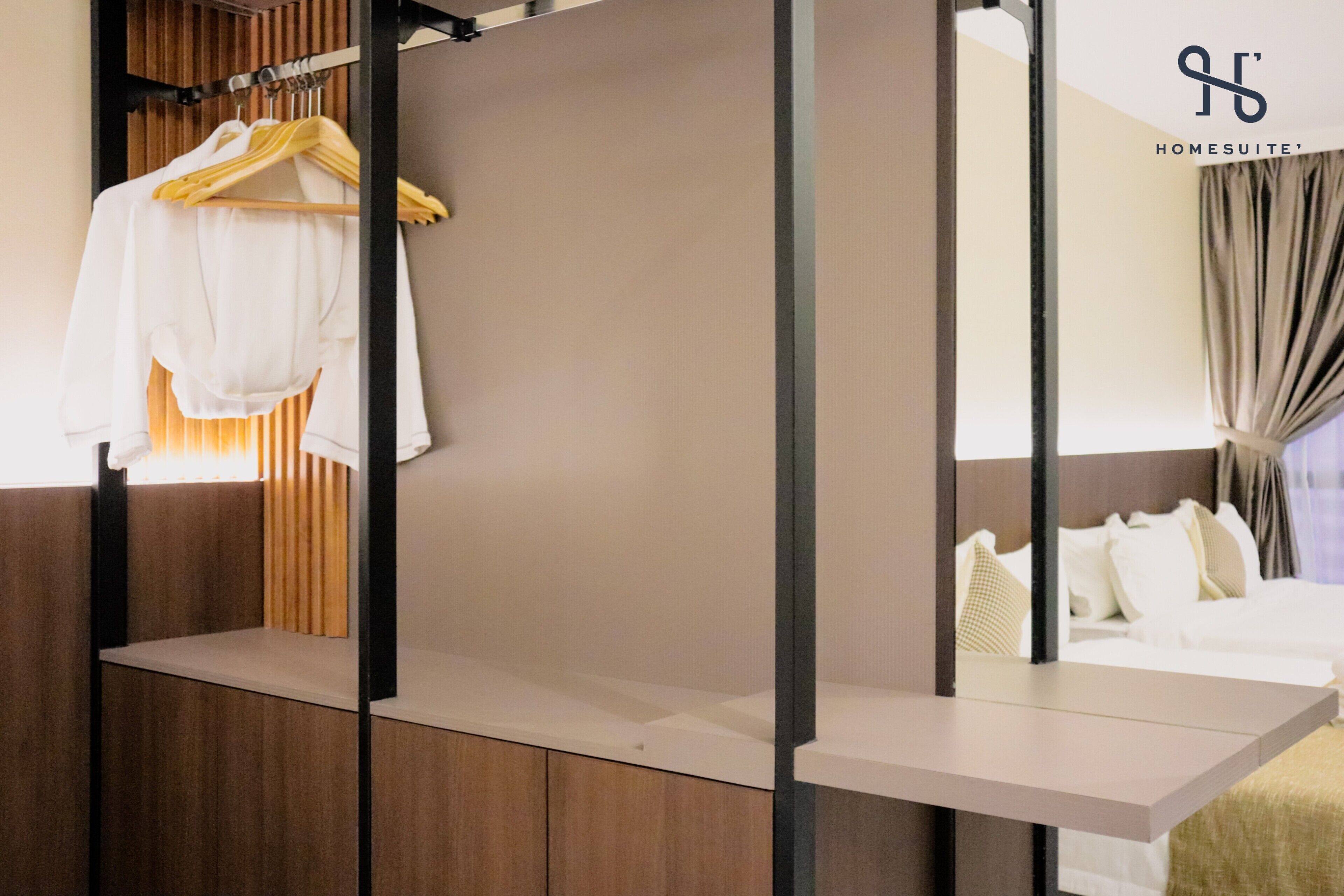 A hotel room with a wooden panel wall, a hanging robe, a bed with white bedding, and a window with curtains.