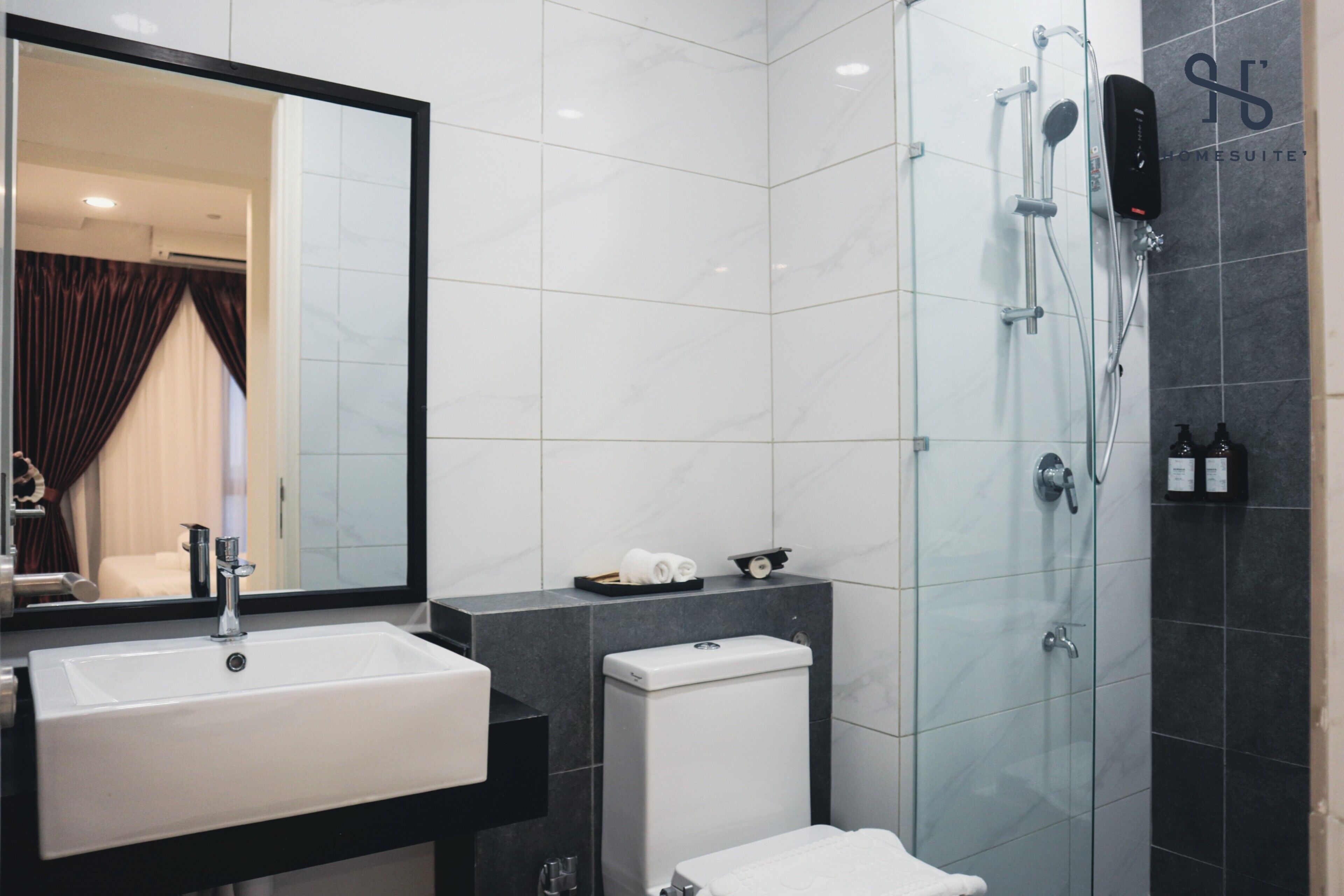 Un baño moderno con lavamanos blanco, inodoro y ducha con mampara de vidrio.
