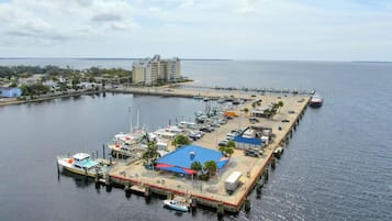 Uma marina com barcos atracados, um cais que se projeta na água e um edifício com vários andares ao fundo.