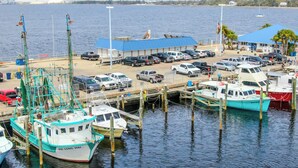 Een jachthaven met verschillende boten afgemeerd, een gebouw met een blauw dak, en een parkeerplaats met meerdere voertuigen.