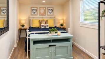 A bedroom with a bed, bedside tables, a dresser, a mirror, and artwork on the wall.