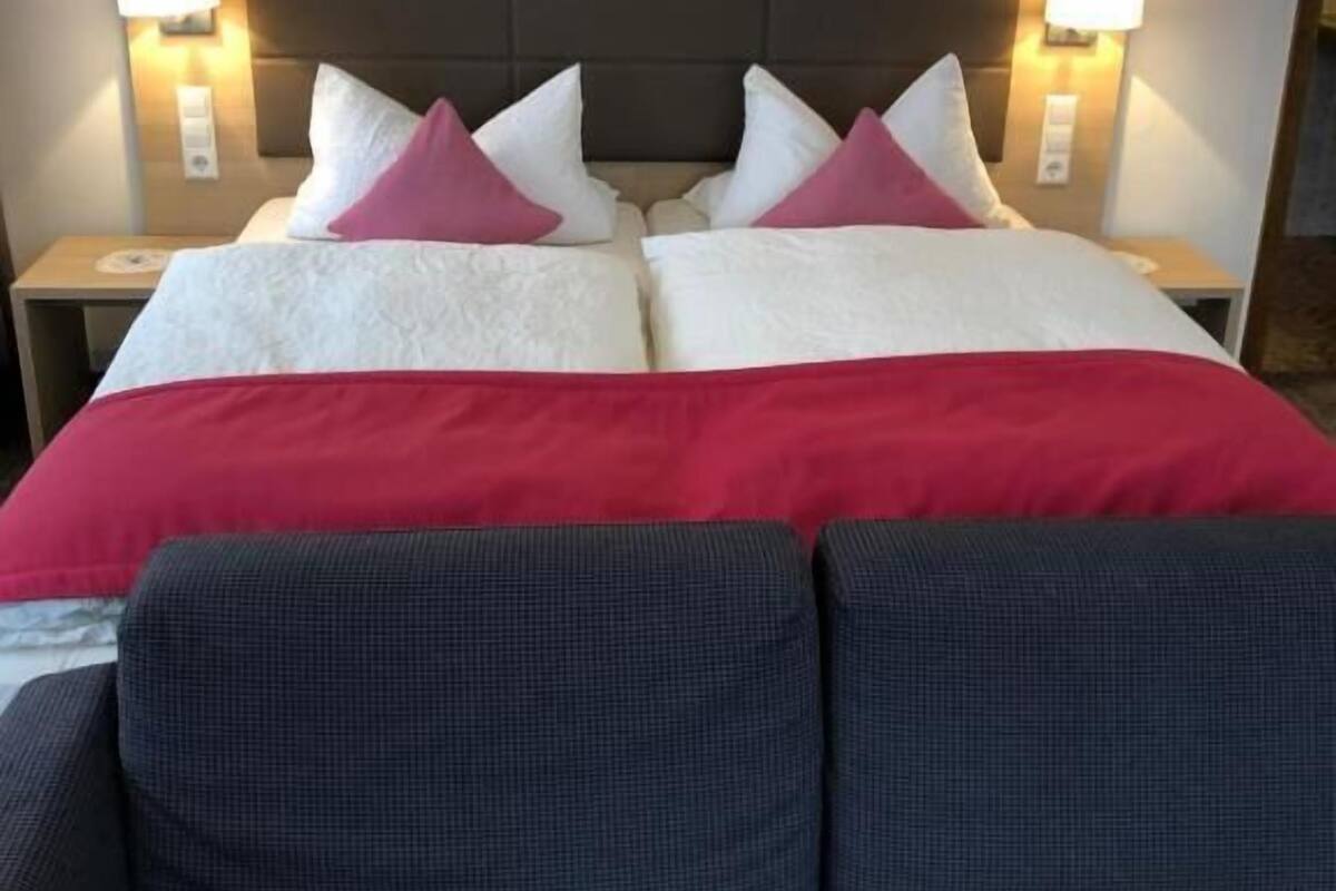 A hotel room with a large bed, two bedside tables, and a sofa.