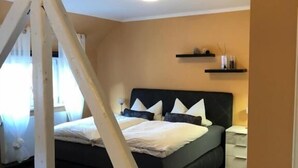 Un dormitorio con cama, mesitas de noche, cabecera y lámpara en el techo.