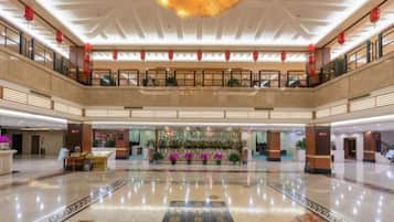 A spacious lobby with a high ceiling, a central floral arrangement, and a reflective floor.