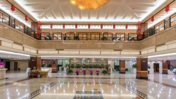 Un vestíbul ampli amb una mostra floral central, un sostre alçat amb un penjoll decoratiu i un sòl de marbre polit.