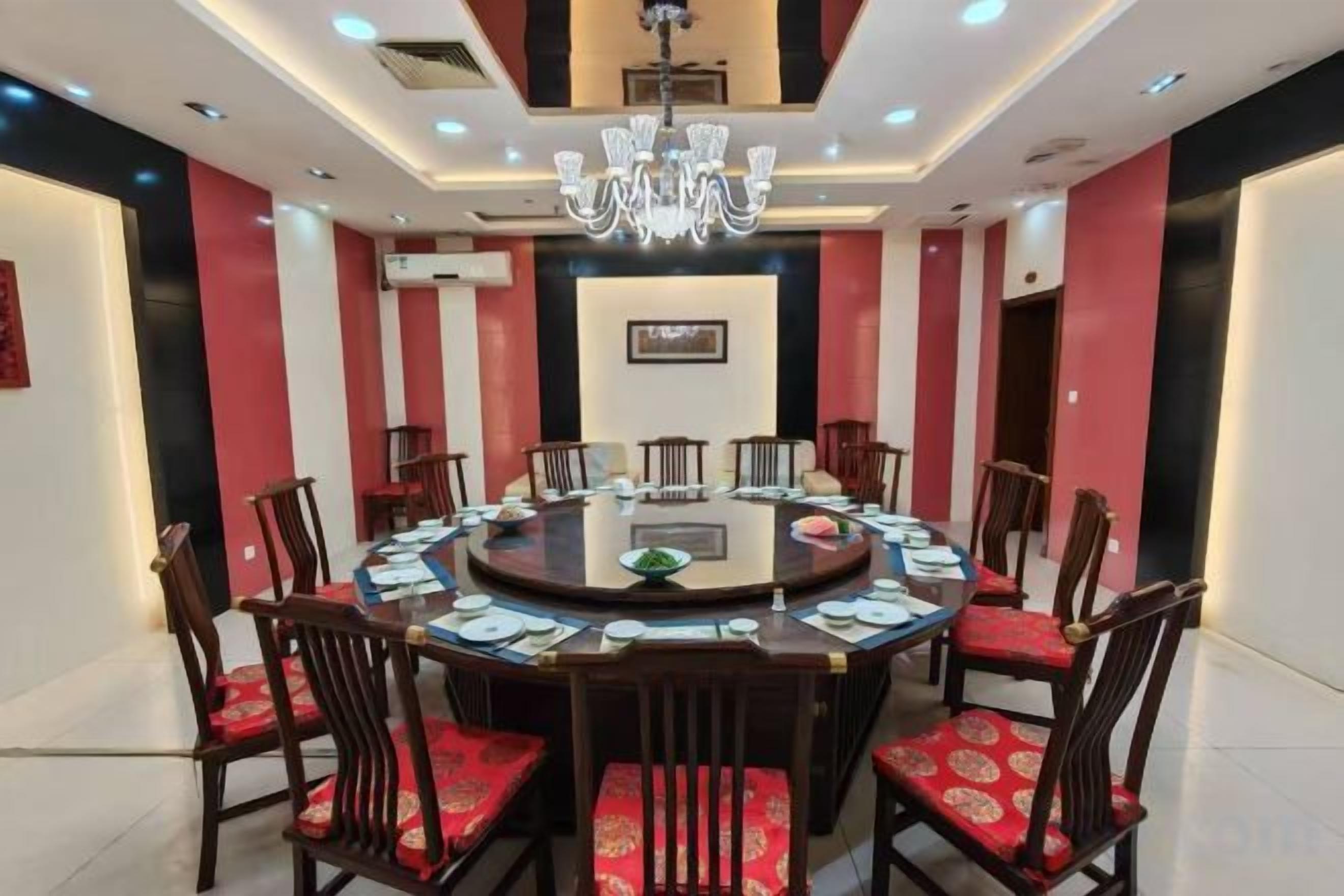 A conference room with a round table, chairs, and a chandelier.