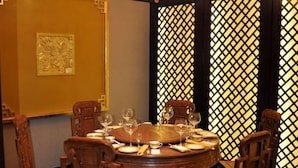 A round dining table set with chairs, a decorative wall with a lattice pattern, and a framed artwork on the wall.