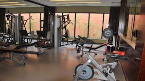 A gym with various exercise equipment, including treadmills and weight machines, and large windows offering a view of the outdoors.