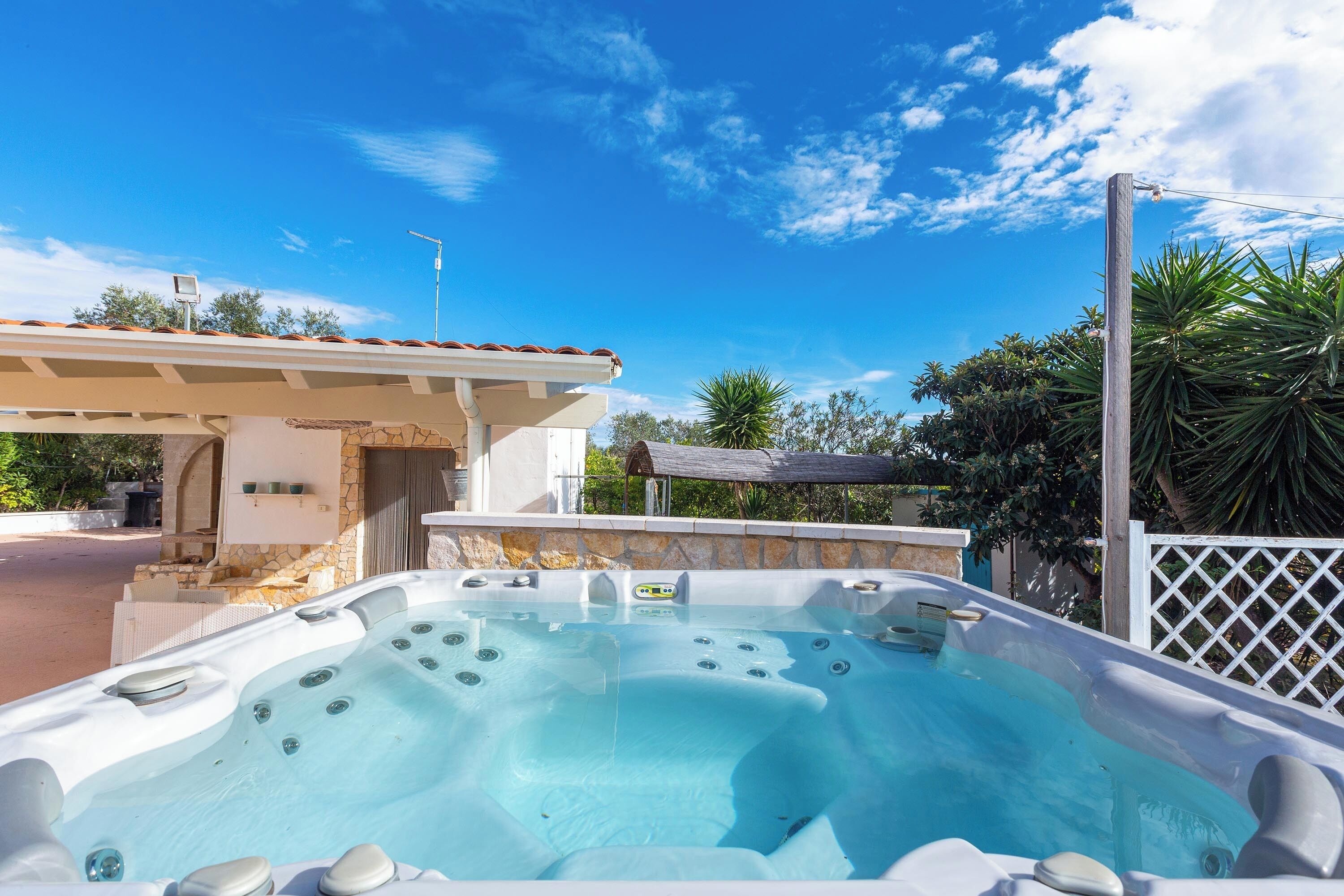 Ein Whirlpool mit Steinwand und einer Pergola im Hintergrund.
