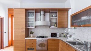 A modern kitchen with wooden cabinets, a stainless steel sink, a microwave, and a built-in oven. - Escape to Apulia by BarbarHouse (Pulsano)