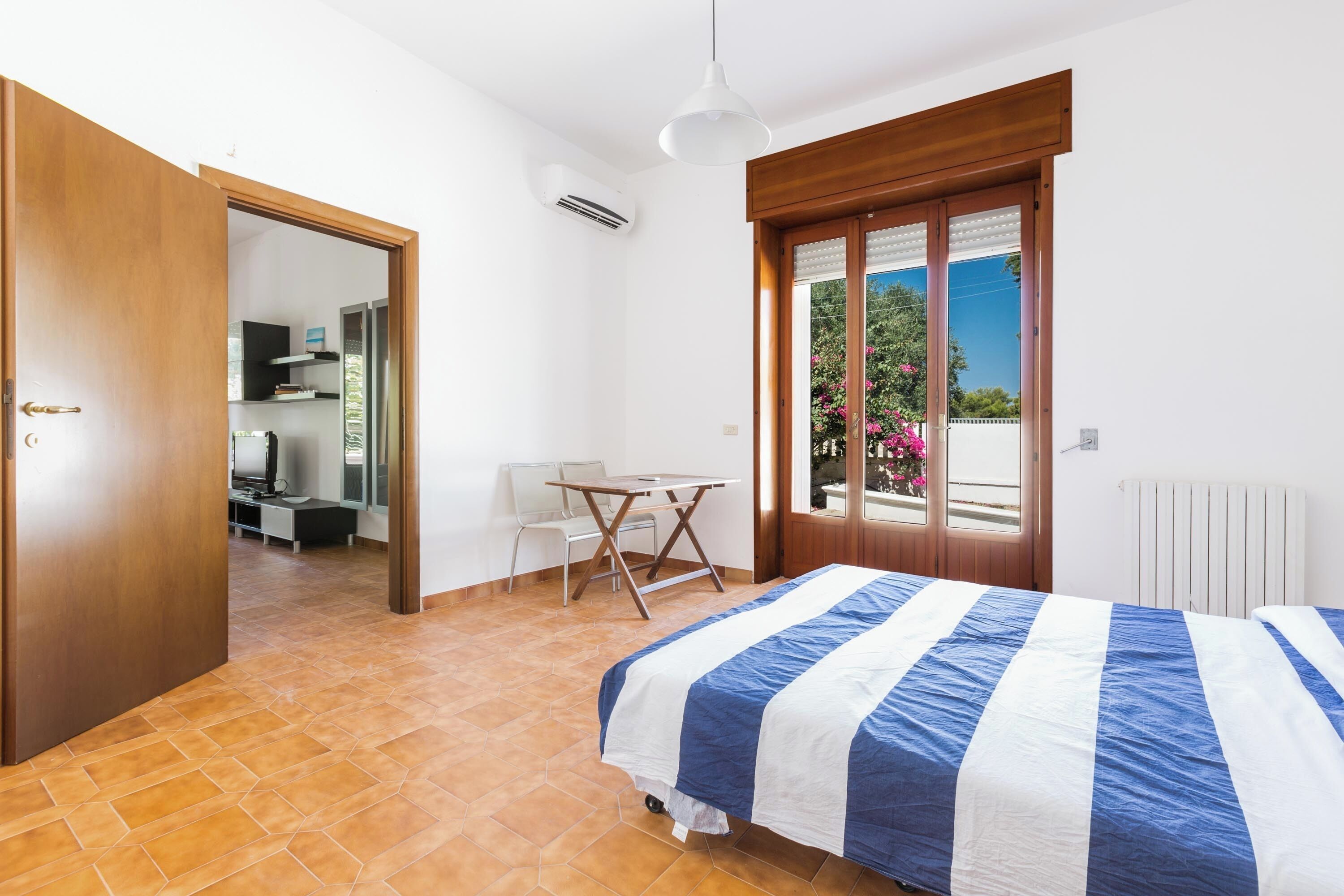 Ein Schlafzimmer mit einem Bett, einem Fenster mit Blick, einer Tür und einem kleinen Tisch mit Stühlen.