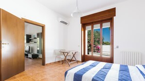 A bedroom with a bed, a window with a view, a door, and a small table with chairs. - Escape to Apulia by BarbarHouse (Pulsano)