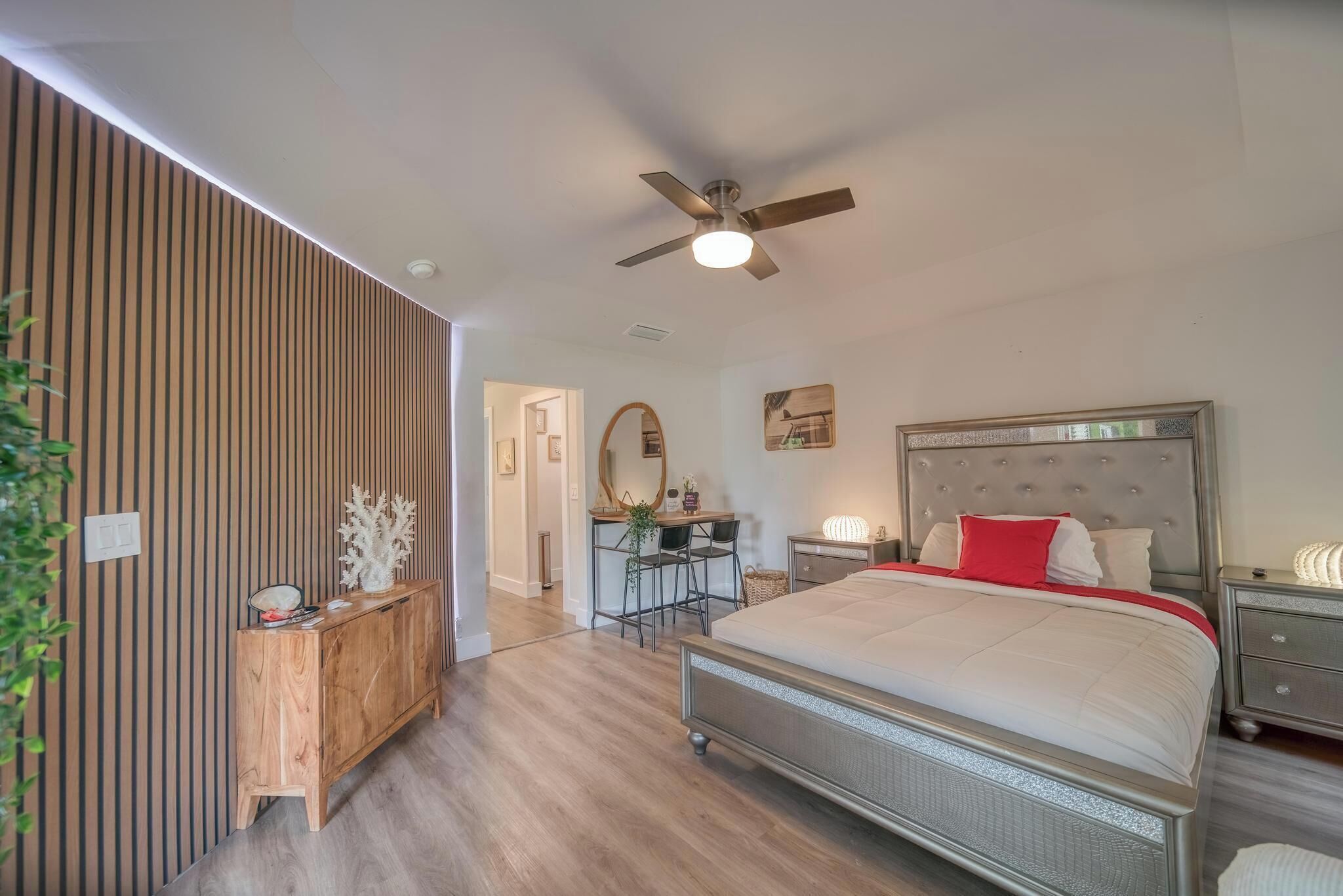 Un dormitorio moderno con cama, mesitas de noche, escritorio y ventilador de techo.