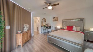 A modern bedroom with a bed, bedside tables, a desk, and a ceiling fan. - The Bright Haven in Cape Coral  (Cape Coral)