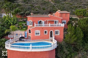 Ein mehrgeschossiges Gebäude mit Pool, umgeben von Grünflächen und Hügeln.