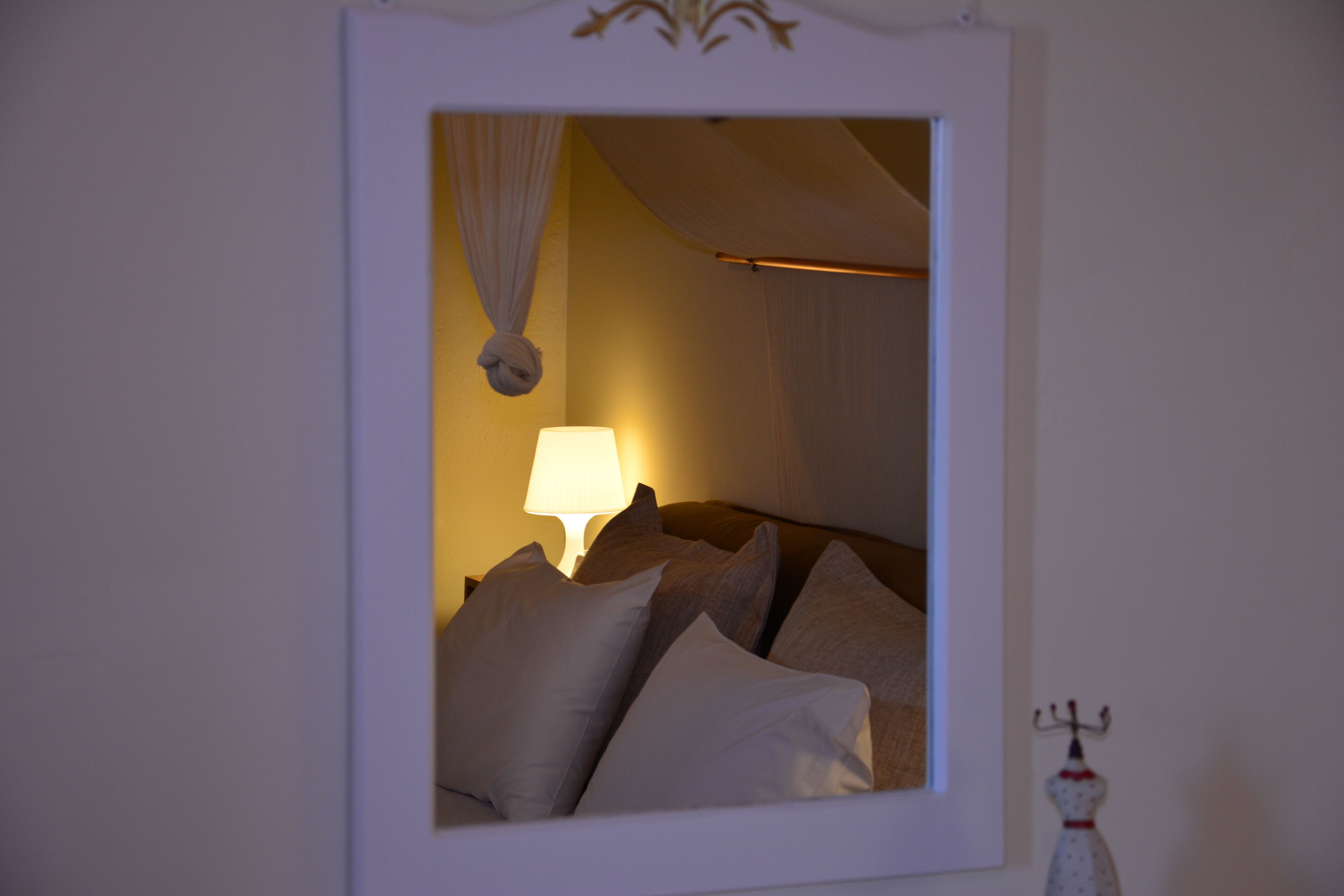 A bedroom with a bed, pillows, a lamp, and a wall-mounted decoration.