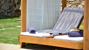 Un letto di legno con un materasso bianco, un asciugamano viola e un bicchiere di vino rosso.