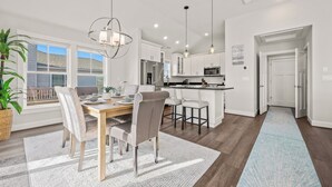 A modern kitchen with white cabinets, stainless steel appliances, and pendant lighting.