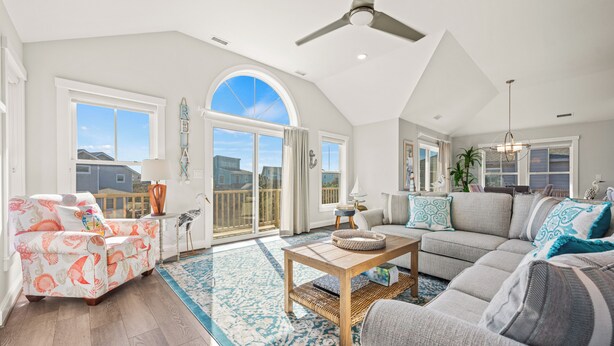 A spacious living room with a large window, a ceiling fan, and a view of the outside.
