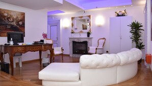 Una sala de estar con un sofá blanco, una mesa de centro de madera, una chimenea y un espejo grande.