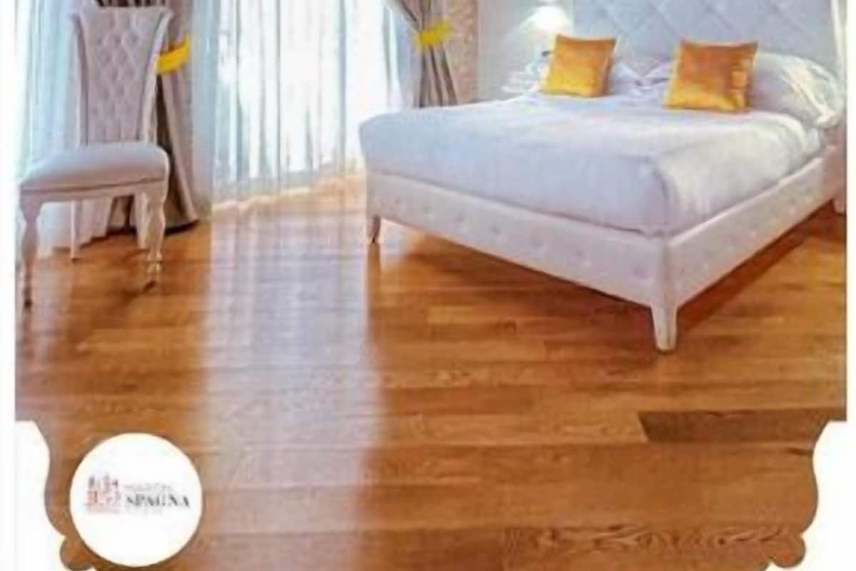 A bedroom with a wooden ceiling, a bed with white bedding, and a chair.