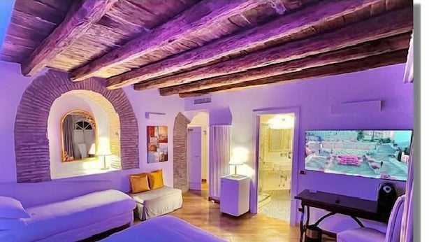Una habitación con una cama, un escritorio y un televisor. Hay dos lámparas sobre el escritorio.