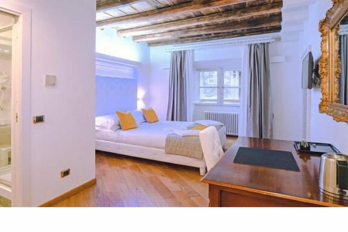 A bedroom with a bed, bedside table, and a window with curtains.