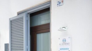 Une entrée moderne avec une porte en verre, un volet métallique et une enseigne indiquant « AL CONSOLE DEPENDANCE ».
