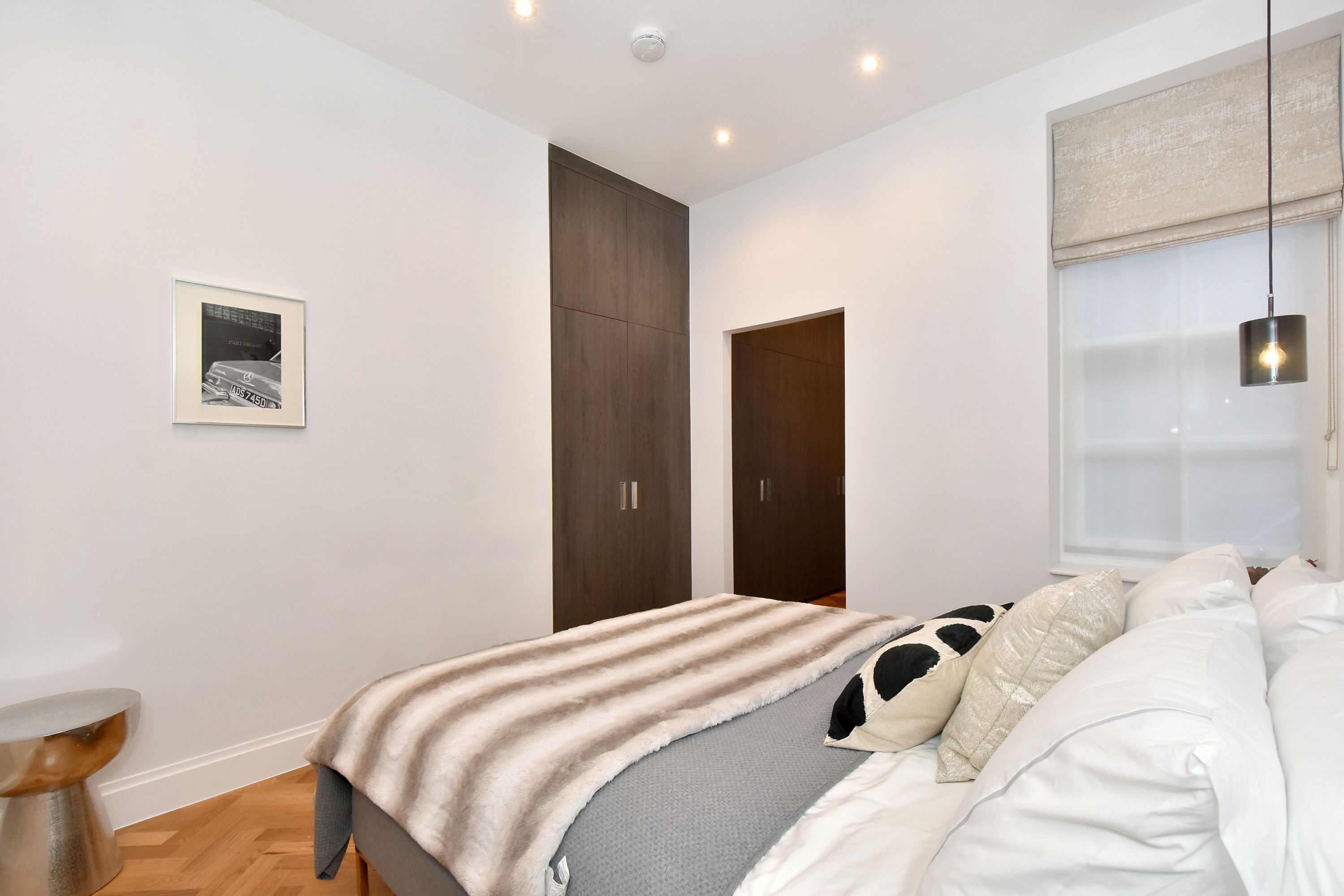 Ein Schlafzimmer mit einem Bett, einem Nachttisch, einem Kleiderschrank und einem Fenster mit Blick.
