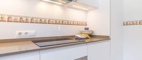 A modern kitchen with white cabinets, a stainless steel oven, and a backsplash with food illustrations.