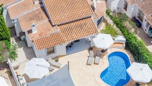 Una propiedad residencial con piscina, mobiliario de exterior y techo de tejas.