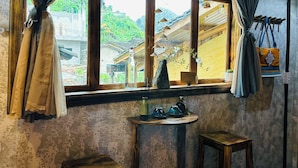 A room with a large window, wooden furniture, a small table with teapots, and a view of traditional buildings outside.
