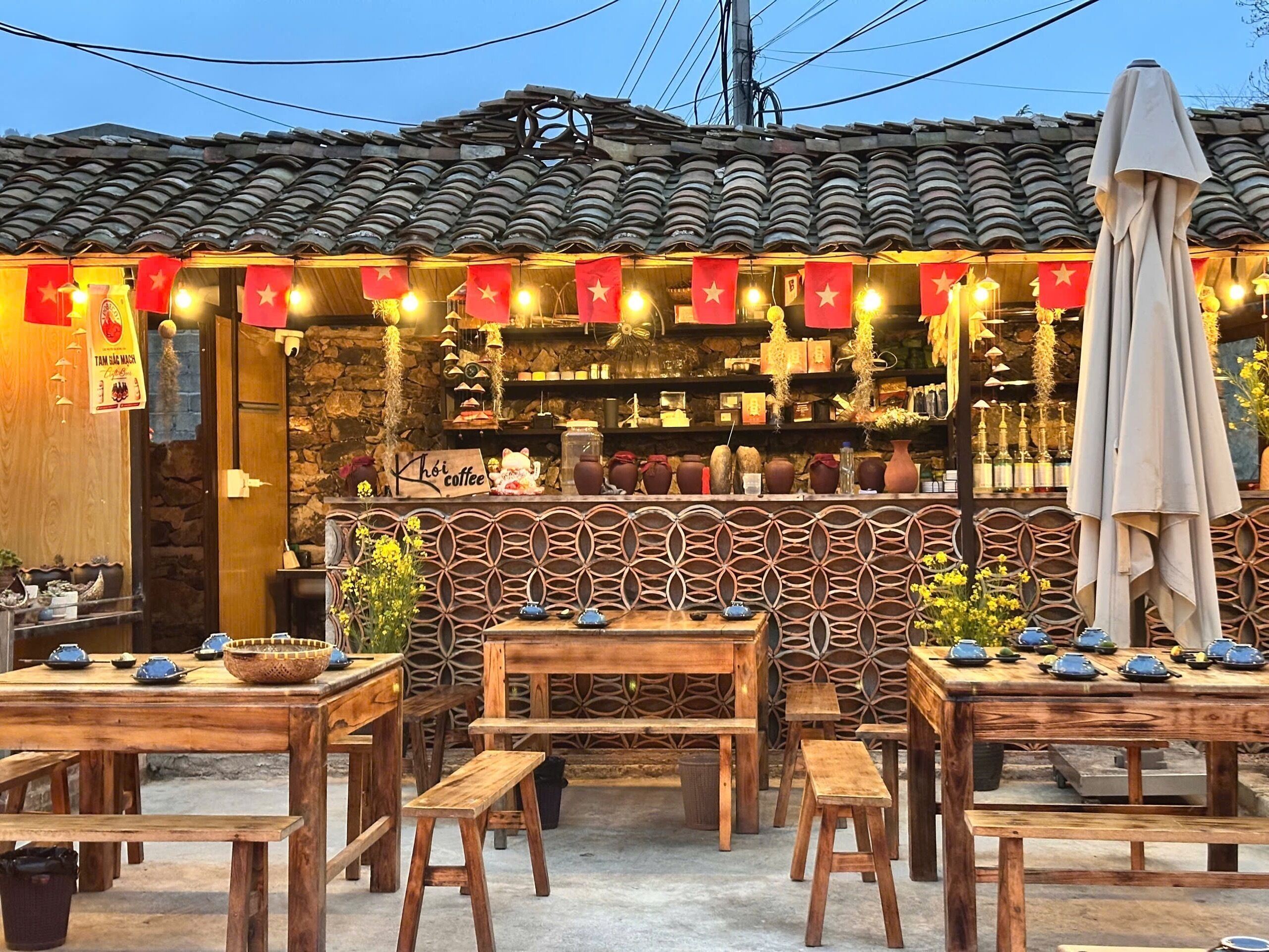 A traditional Vietnamese coffee shop with wooden furniture and a tiled roof.