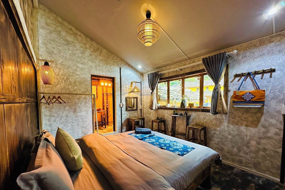 A cozy bedroom with a bed, wooden wardrobe, and a window with curtains.