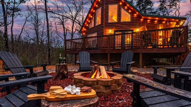 A log cabin with a deck, outdoor seating, and a fire pit. - Firefly Ridge! Cozy, Fishing Pond, Hot Tub, Fire Pit! (Sevierville)