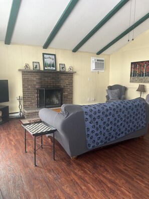 Una habitación acogedora con chimenea, un sofá, una mesita y una cama con colcha estampada.