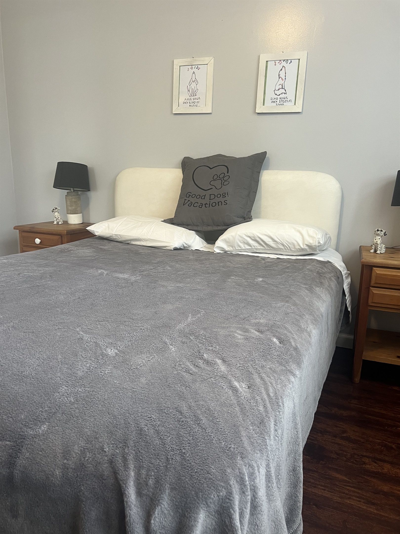 A bedroom with a bed, two nightstands, a lamp, and two framed pictures on the wall.