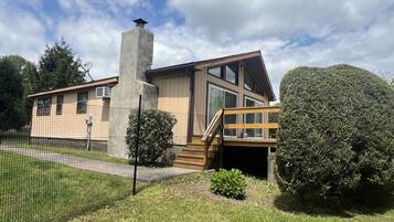 A modern two-story house with a large chimney, a covered porch, and a fenced yard.