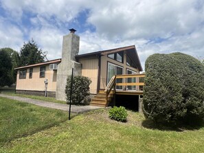 Ein modernes, zweistöckiges Haus mit großem Schornstein, einer überdachten Veranda und einem umzäunten Garten.